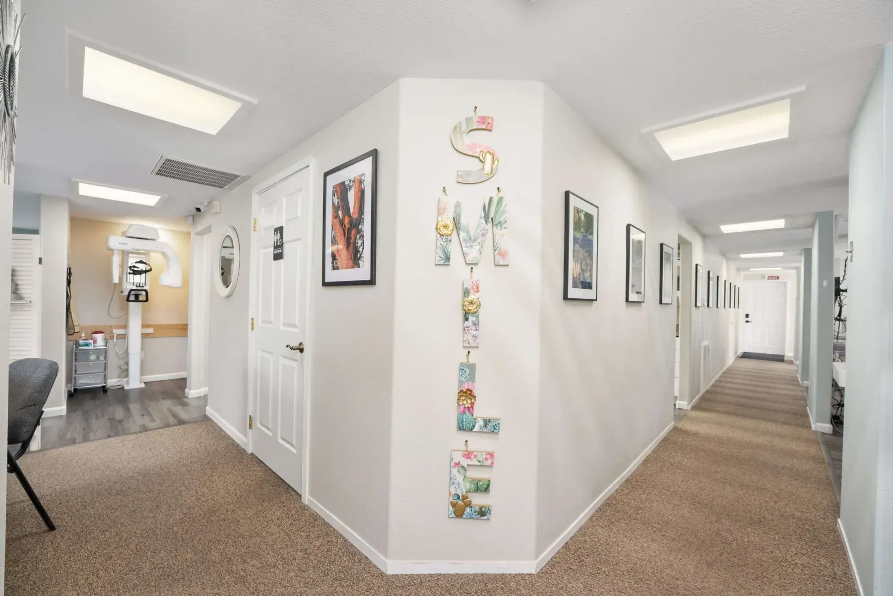 The hallway to the treatment rooms, with a SMILE sign and local artwork